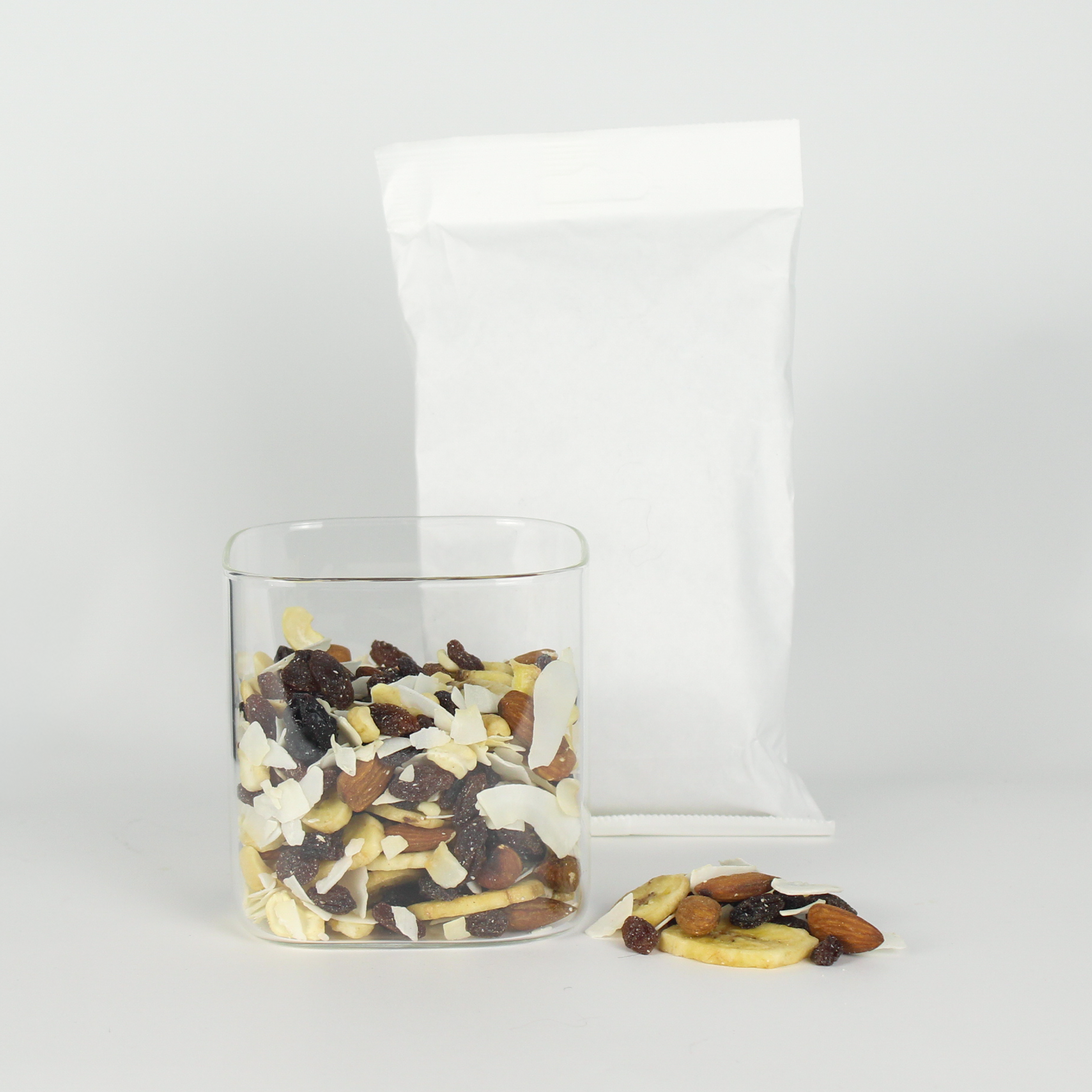 Glass jar filled with a mix of dried fruits and nuts on a white background