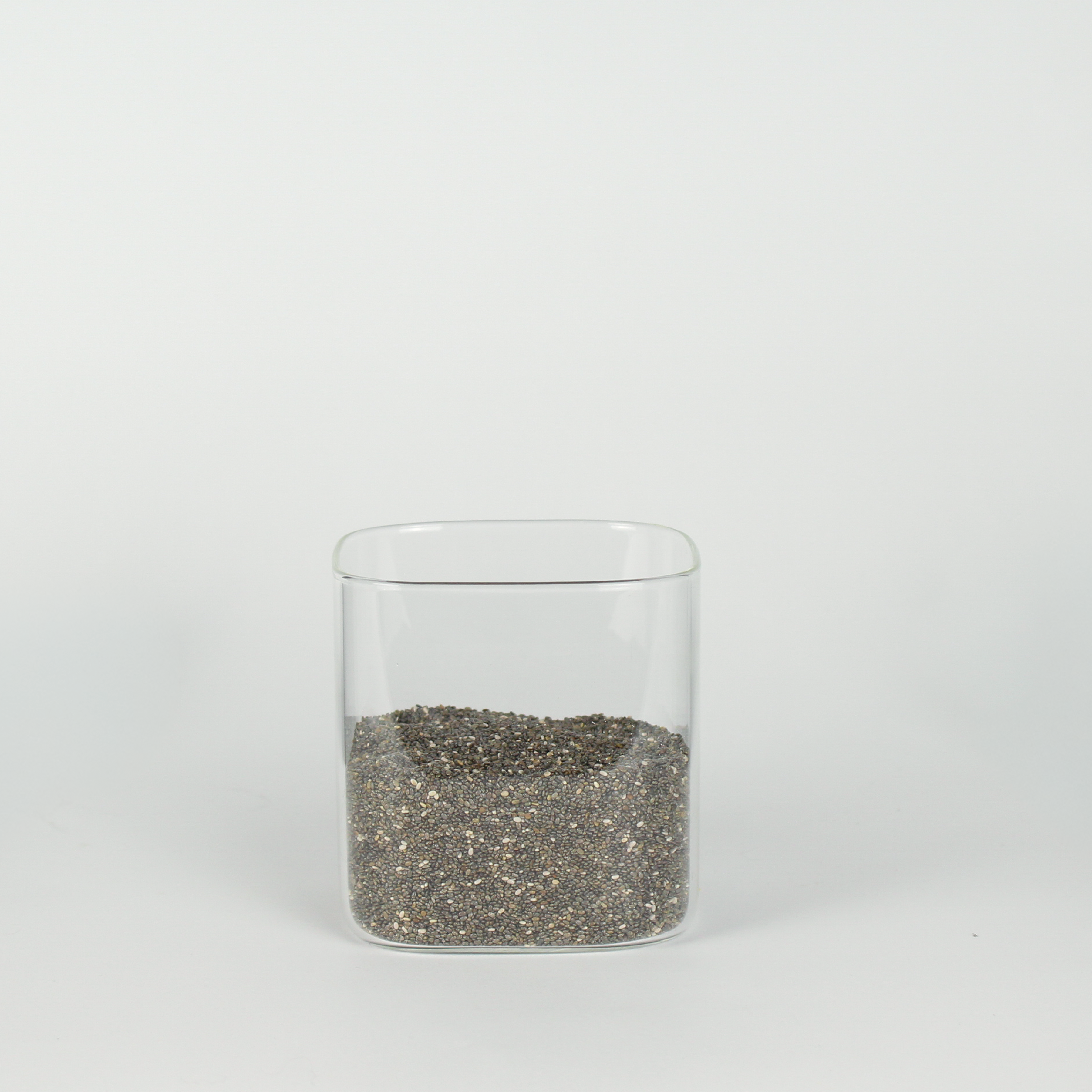Clear glass container with chia seeds on a white background