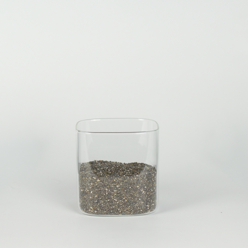 Clear glass container with chia seeds on a white background